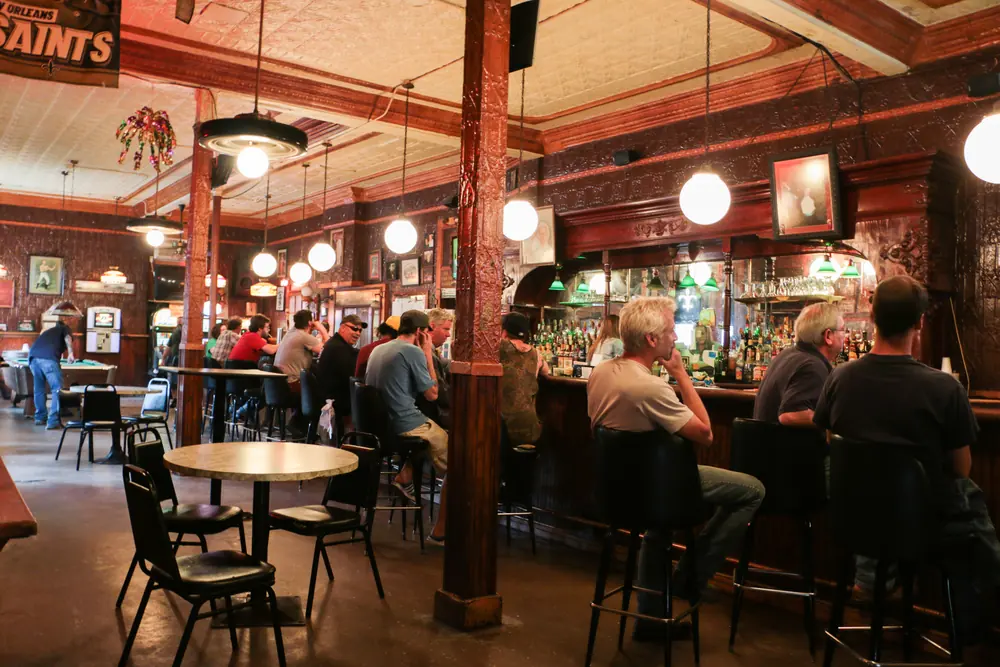 The long wooden bar at Bud Rip’s, with patrons seated under pendant lights.