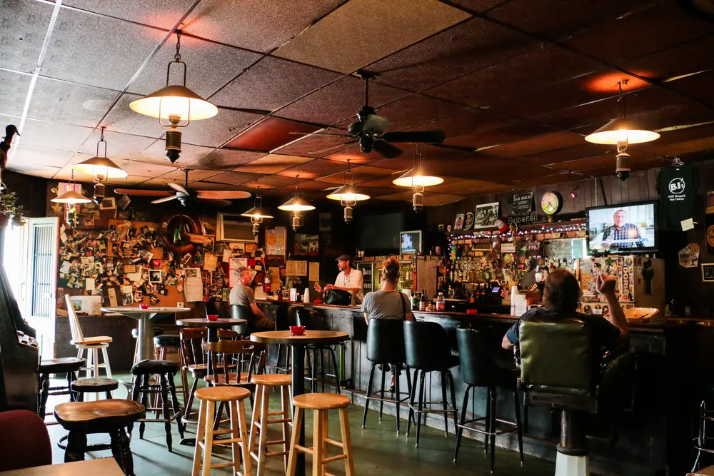 The bar room at BJ’s Lounge, with pendant lamps, bar stools and a wall of memorabilia.