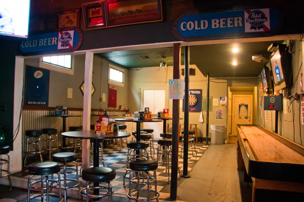 Inside Markey’s Bar: checkerboard floor, bar stools and a shuffleboard table.