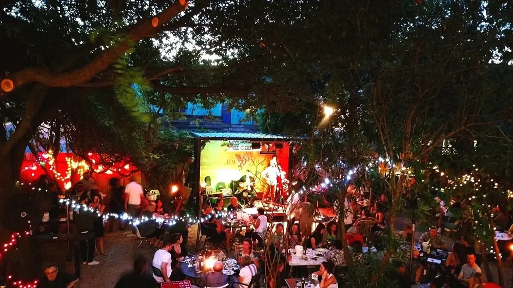 Bacchanal’s backyard at night, with string lights, a stage and people at tables.