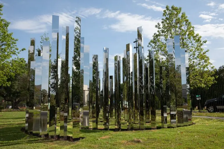 Tall mirrored panels standing in a grove on the lawn of the Besthoff Sculpture Garden.