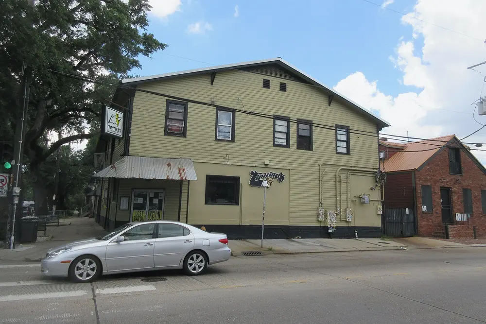 Tipitina’s, a yellow two-story clapboard building at the corner of Napoleon Avenue and Tchoupitoulas Street, with a brick building beside it.