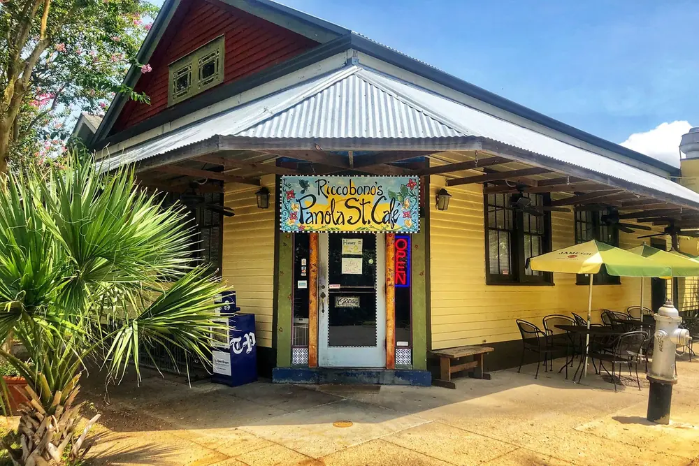 Riccobono’s Panola Street Café, a yellow wood building with a metal roof, a palm and a painted sign over the door.